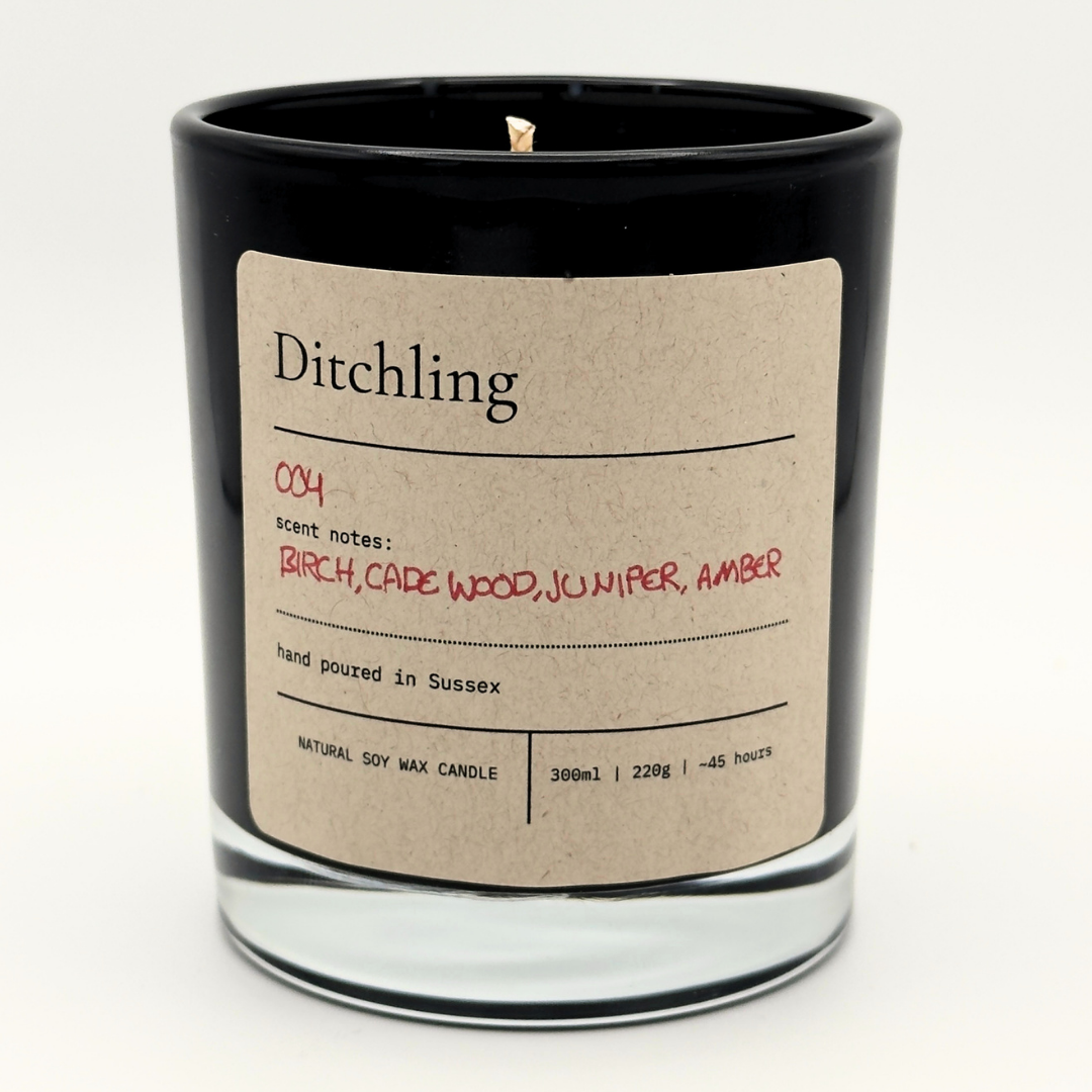 Ditchling 004 Embers scented soy candle in a black glass jar with a kraft paper label, featuring birch, cade wood, juniper and amber scent notes.