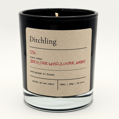 Ditchling 004 Embers scented soy candle in a black glass jar with a kraft paper label, featuring birch, cade wood, juniper and amber scent notes.