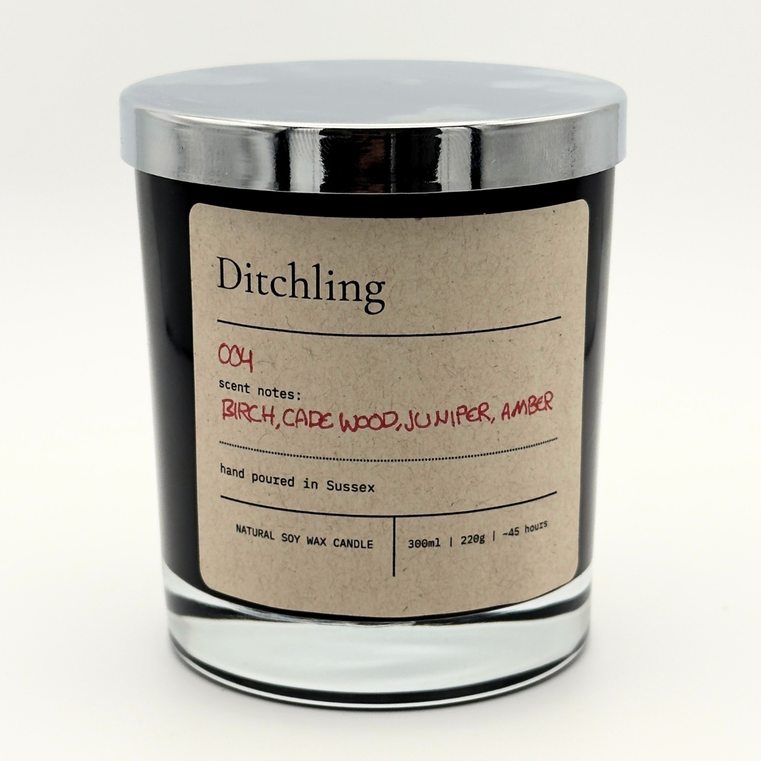 Ditchling 004 Embers scented soy candle in a black glass jar with a kraft paper label, featuring birch, cade wood, juniper and amber scent notes.