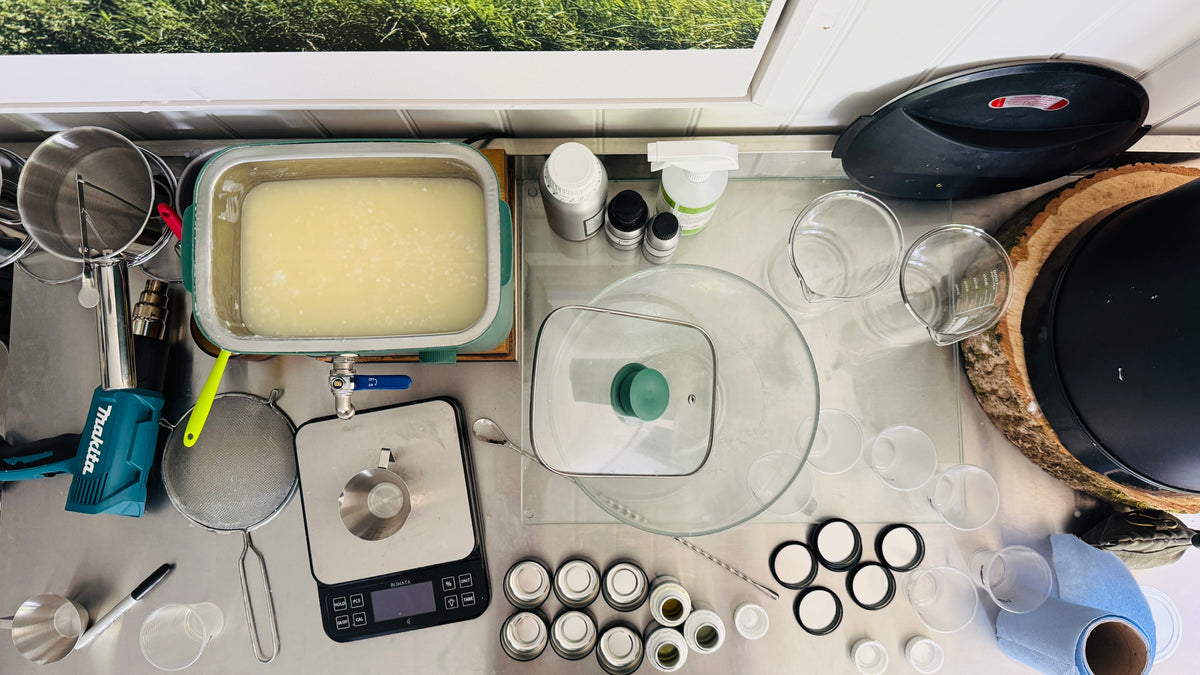 Bird’s-eye view of the Ditchling candle-making workspace, showing a wax melter filled with soy wax, scales, mixing bowls, jugs, fragrance bottles and candle-making tools laid out across the workbench.