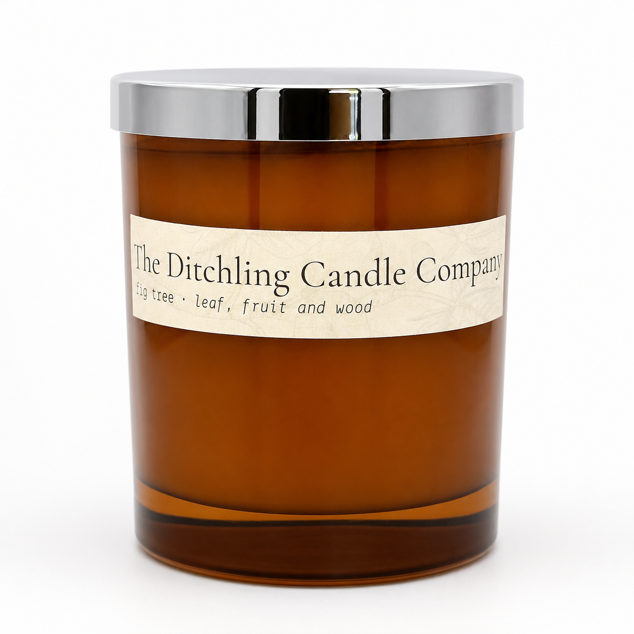 Amber glass fig tree scented soy candle by The Ditchling Candle Company with a silver lid, shown on a clean white background.